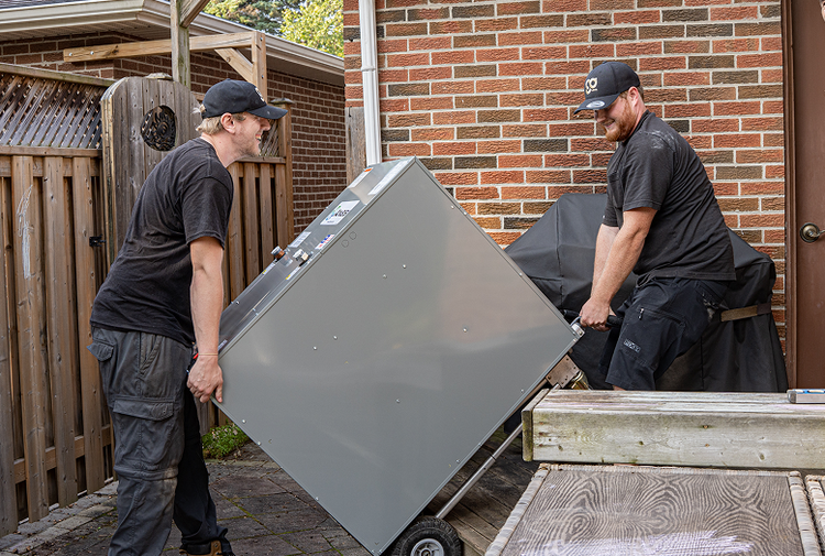 Two men moving a large metal appliance 